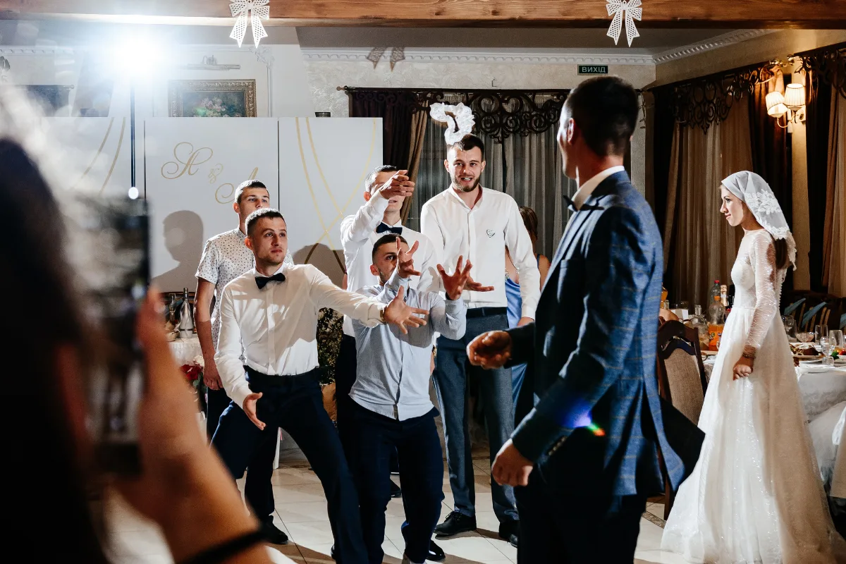 Indoor And Outdoor Wedding Venues: 9 Smart Differences Every Couple Should Know Guests reaching for the bouquet toss during an indoor wedding reception, capturing energy, lighting, and celebration flow.