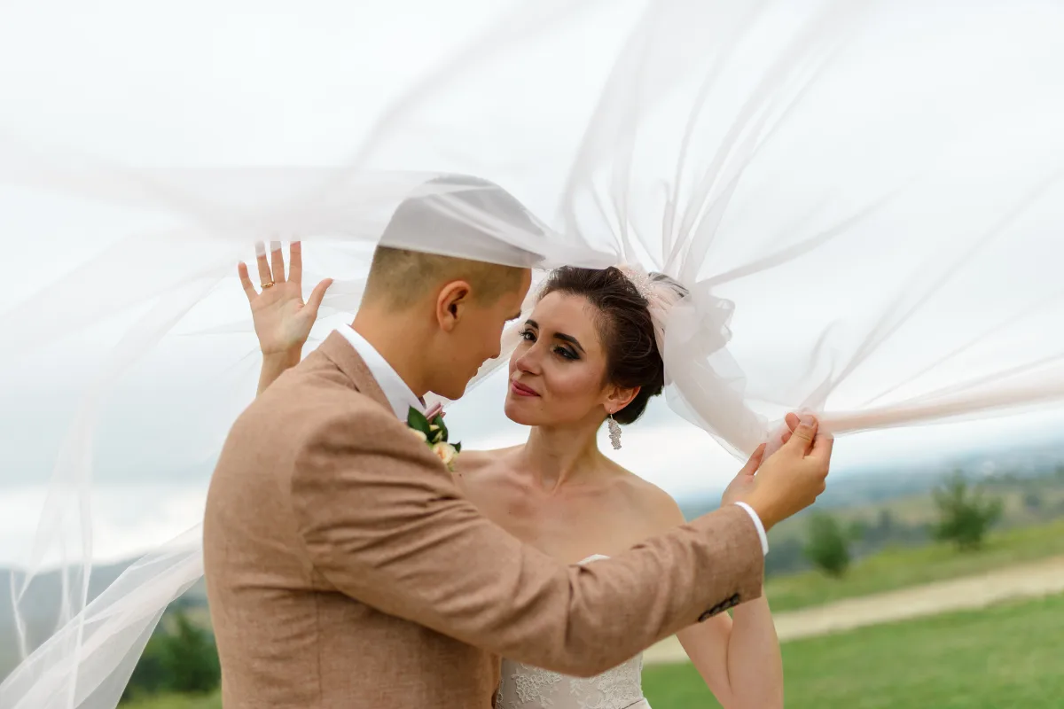 Indoor And Outdoor Wedding Venues: 9 Smart Differences Every Couple Should Know Bride and groom sharing a quiet moment under a flowing veil, comparing indoor and outdoor wedding venues for romance and scenery.